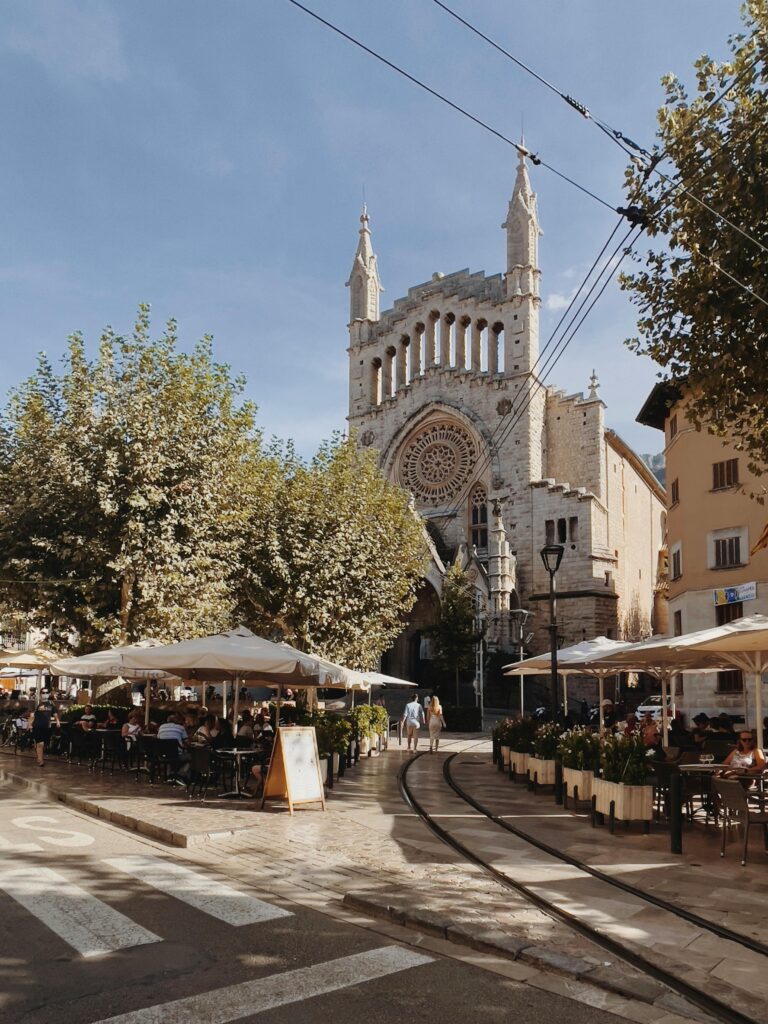 Beautiful sunny day at the iconic Sant Bartomeu Church with outdoor cafes and tramway tracks.